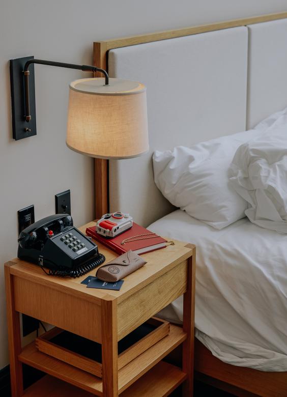 A bedside table with old-school phone, camera, and journal.