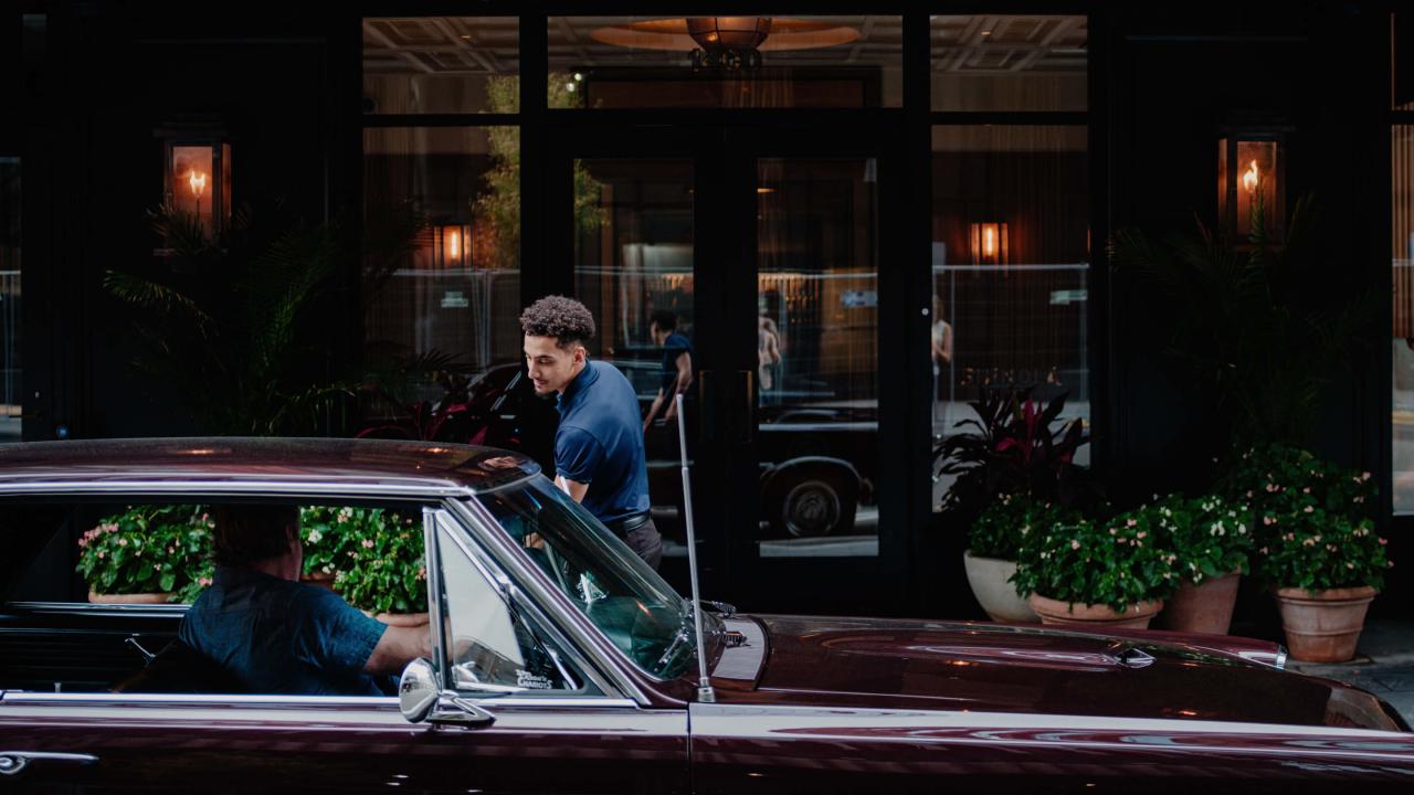 person getting in car in front of hotel