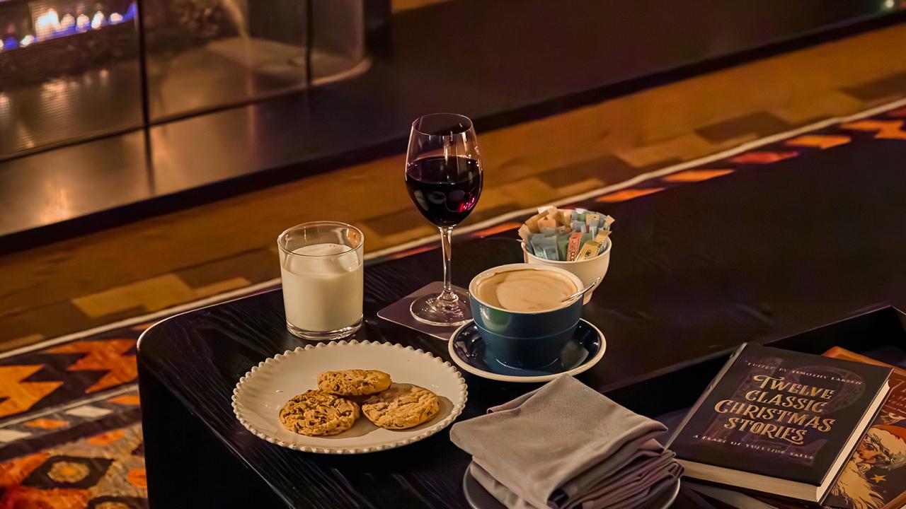 An in-room spread of milk and cookies, hot chocolate, and wine next to the fireplace.