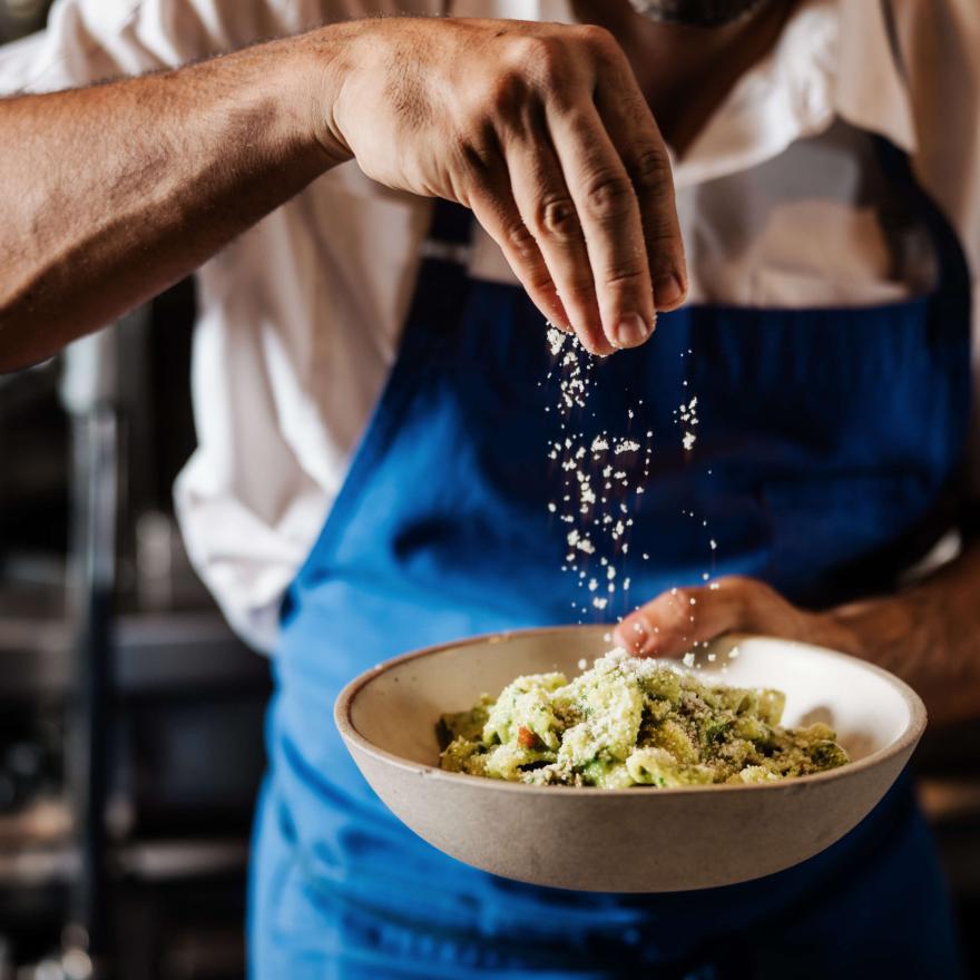Chef sprinkling Parmesan on salad