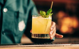 Bartender serving a yellow mixed drink