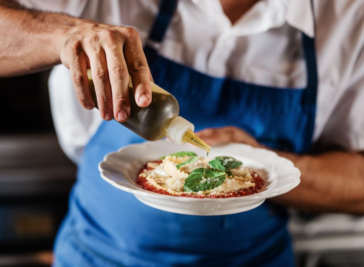 chef sprinkling cheese on a dish
