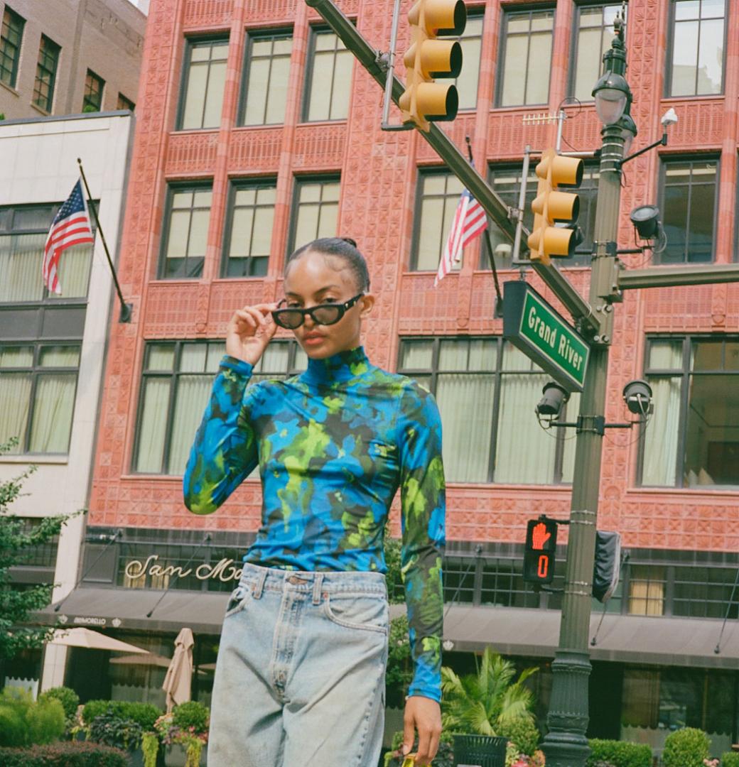 A stylish woman crosses the street in front of Shinola Hotel.