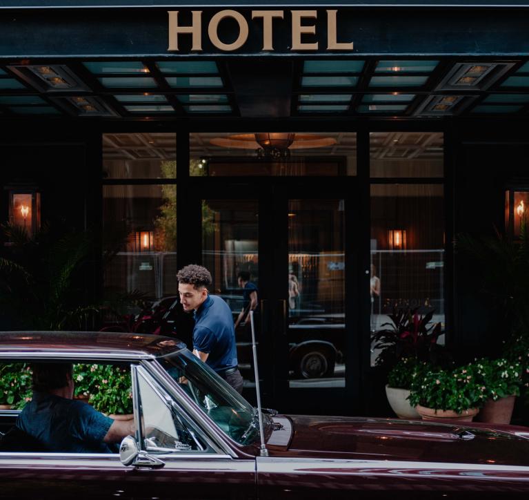 person getting in car in front of hotel