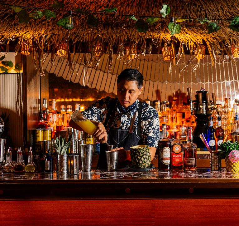 A bartender mixes a tropical cocktail at Evening Bar