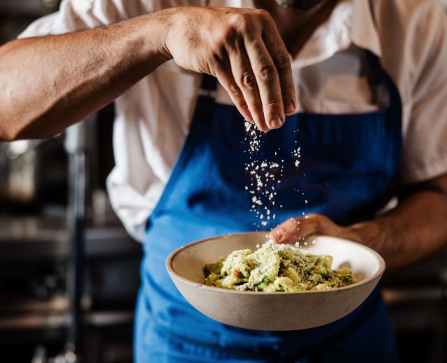 Chef sprinkling Parmesan on salad