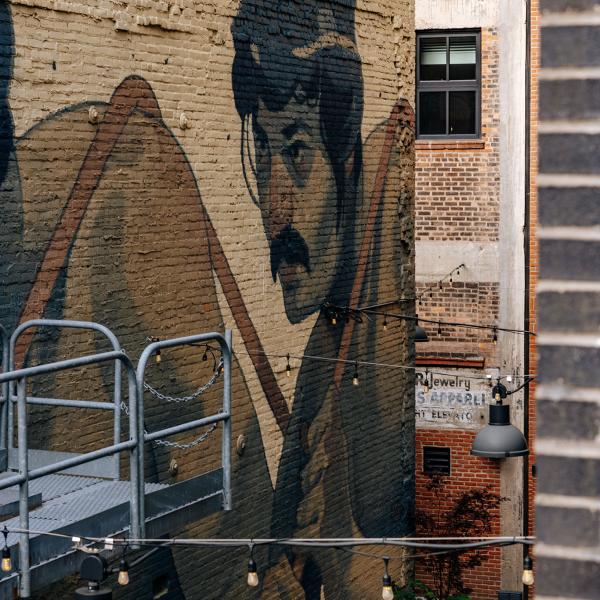 Mural of blue collar workers by Aryz titled "One Man Army" on a brick building